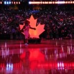 The Toronto Raptors mascot poses in front of a maple logo at center court